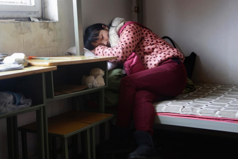 Image: Wang Feng rests on a bed before she leaves for work, at Huaxia Liangtse Massage Training Centre in Zhengzhou, Henan province