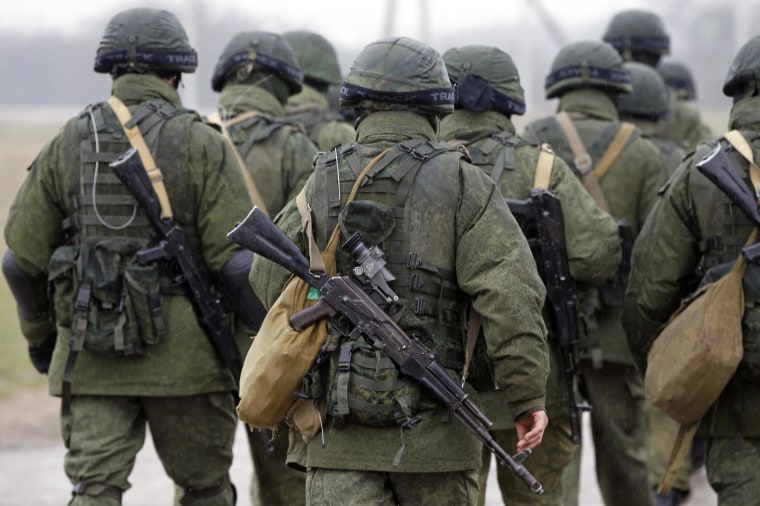 Uniformed men, believed to be Russian servicemen, walk in formation near a Ukrainian military base in the village of Perevalnoye outside Simferopol