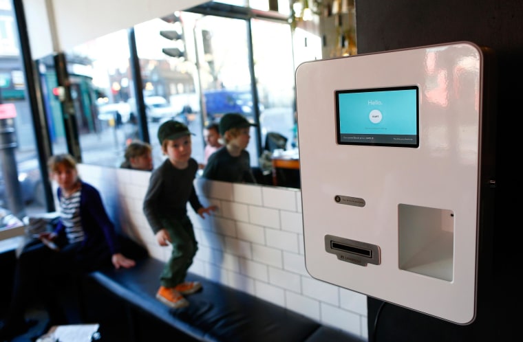 Image: Leo plays on a bench next to a Bitcoin machine at the Old Shoreditch Station Cafe and Bar in east London