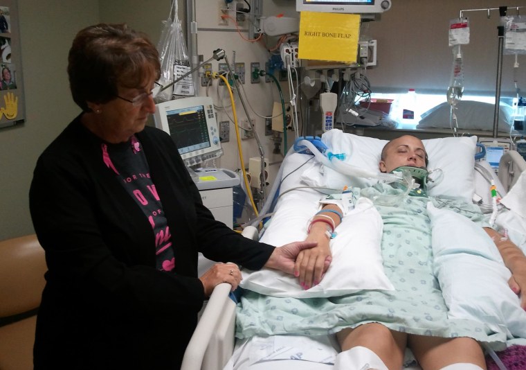 Andrea Vellinga's mother Sandi Voss holds Andrea's hand in the hospital.