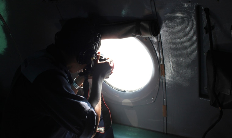 Image: A Vietnamese Air Force officer takes photos from a search and rescue aircraft in the search area for a missing Malaysia Airlines plane