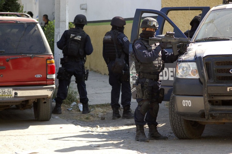 Image: Federal police stand guard during 2010 raid where security forces fought cartel members.