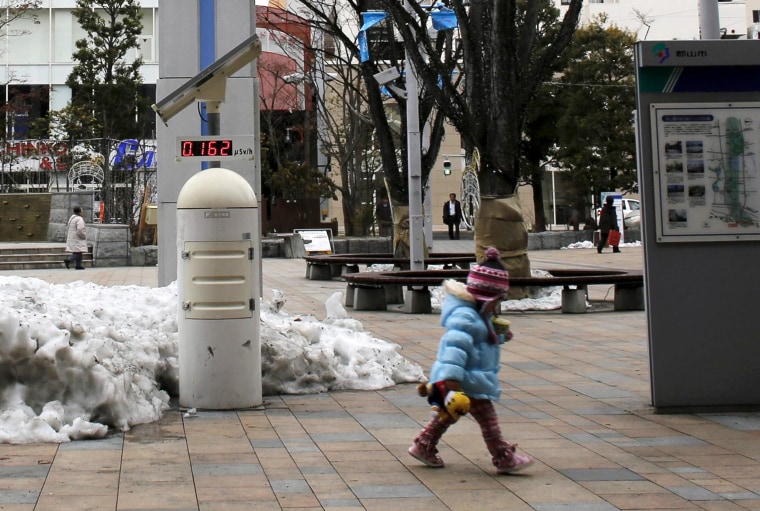 Image: A child walks past a geiger counter