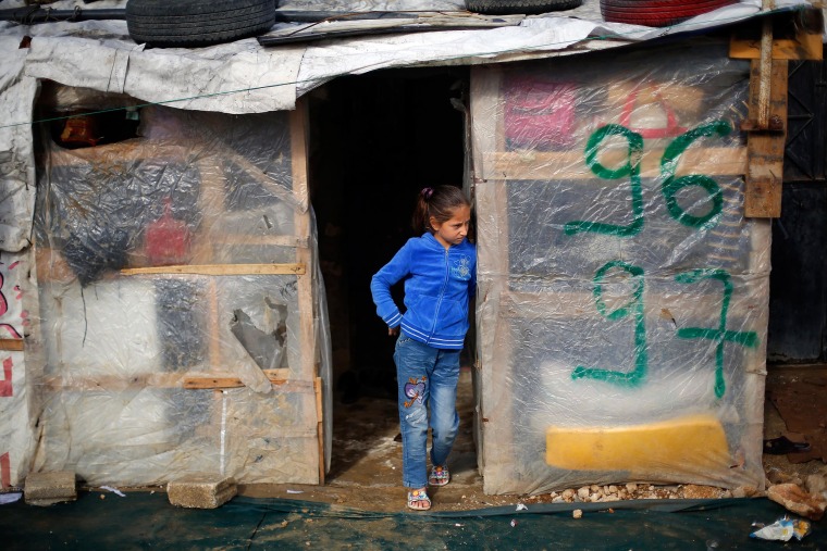 Image: A Syrian refugee child stands outside her shack in the Fayda Camp, some 25 miles east of Beirut