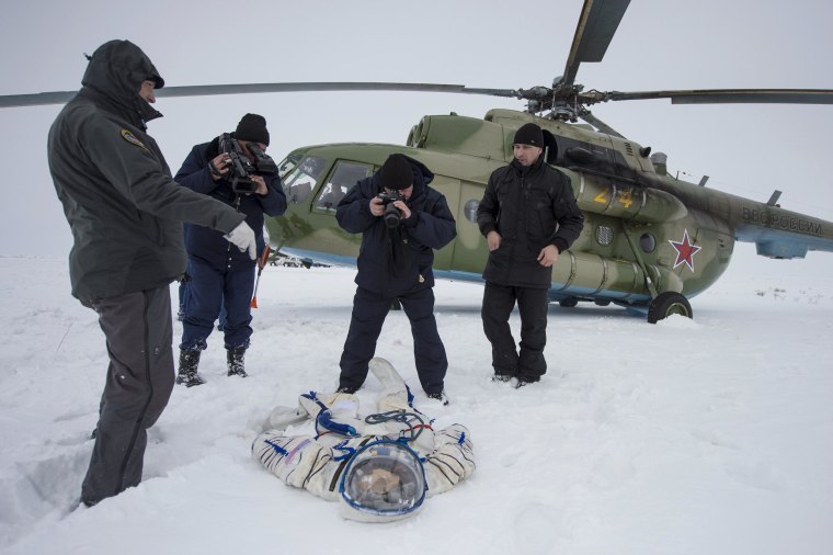 Image: A photographer and an operator document the suit worn by astronaut Hopkins from NASA after the landing of the Soyuz TMA-10M capsule in a remote area southeast of Zhezkazgan