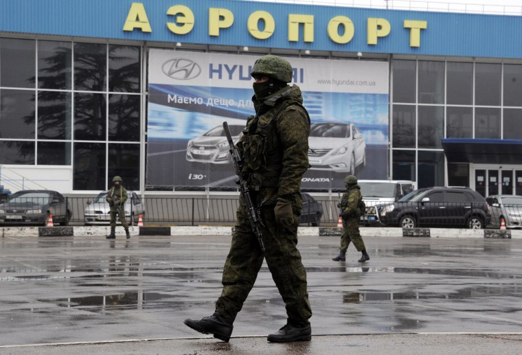 Image: Unidentified armed men patrolling outside Simferopol airport