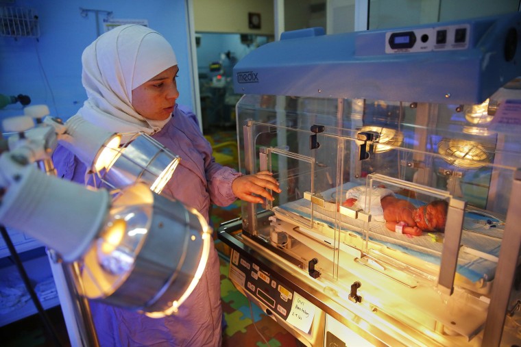 Image: Ahed Hussein, 18, puts her hand on the incubator where her premature newborn daughter rests