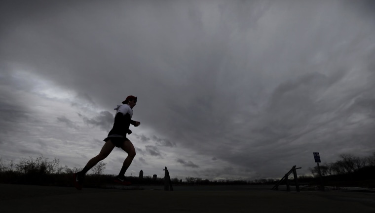 Image: A runner heads down the trail under cloudy skies at Greys Lake Park, on Tuesday, in Des Moines, Iowa.