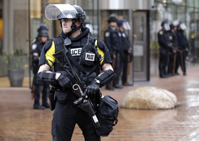 Image: A police officer armed with riot gear stands guard.