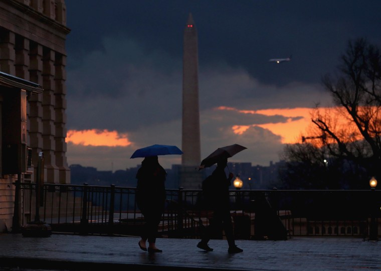 People carry umbrellas as they walk out of the US Capitol, on March 12, 2014 in Washington, DC. The Washington area was hit with a fast moving storm causing temperatures to drop.  