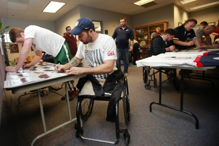Image: 2014 U.S. Paralympic sled hockey team signs autographs