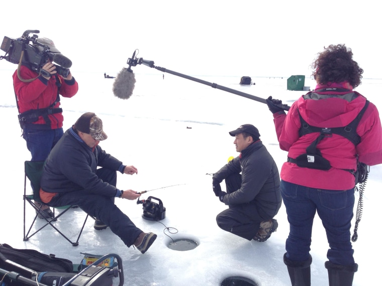 Image: John Yang interviews Minnesota resident Dave Maki, second left, who is ice fishing