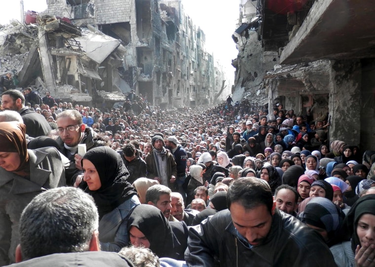 Image: Residents of the besieged Palestinian camp of Yarmouk queuing to receive food supplies in Damascus.
