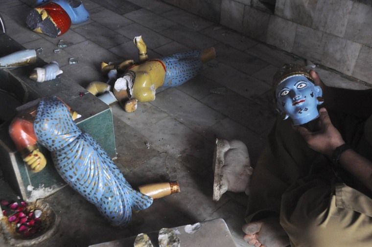 Image: A member of the Hindu community holds a damaged statue inside a temple that was attacked on Saturday night, in Larkana