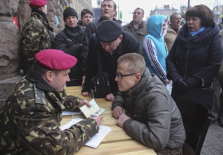 Image: A volunteer speaks with a Ukrainian military officer as he registers for service in the newly-created National Guard in central Kiev