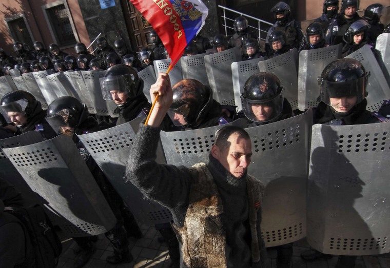 Image: Demonstrator takes part in a pro-Russian rally as riot police stand guard in Donetsk