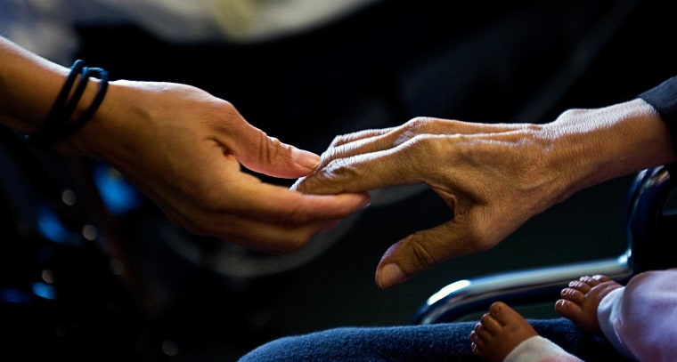 Guadalupe Tinajero, who has late stage Alzheimer's, reaches for her daughter, Cynthia Tinajero's hand.