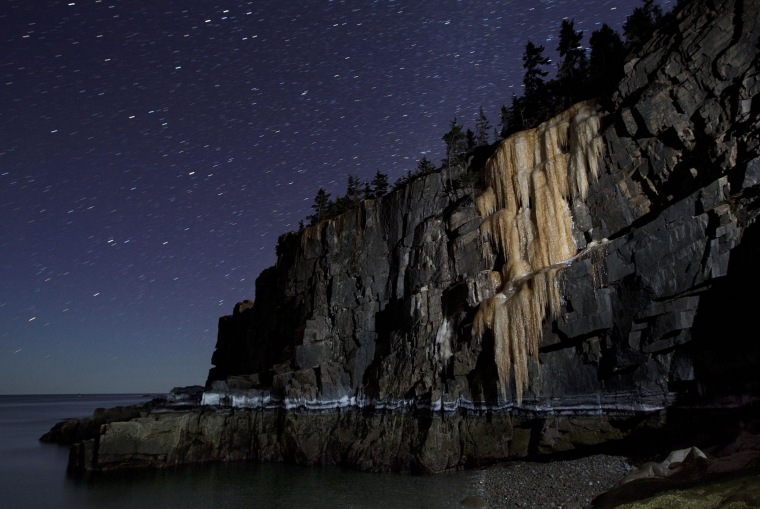Image: Like a frozen waterfall, a wall of ice more than 40-feet-high stretches down to the high-tide line on Otter Cliffs overlooking the Atlantic Ocean, in this time-exposure made on March 6, at Acadia National Park in Maine.