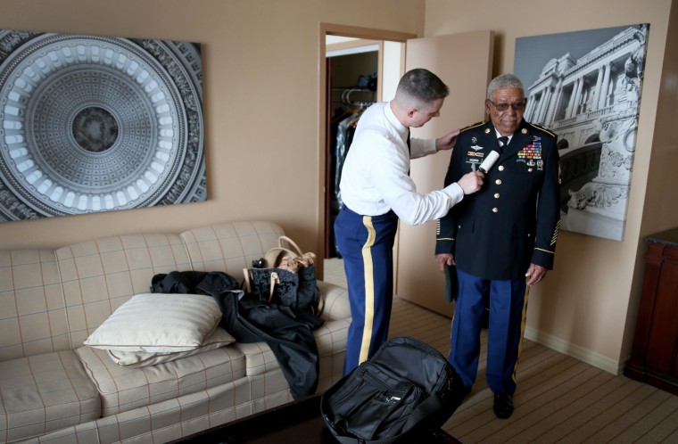 Image: U.S. Army Staff Sergeant Christopher Schneider uses a lint roller on the uniform of U.S. Army Staff Sgt. (Ret.) Melvin Morris, right, a Vietnam War veteran, as they prepare to make their to the White House