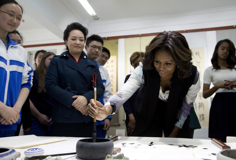 Image: First Lady Michelle Obama tries to write Chinese words with a brush