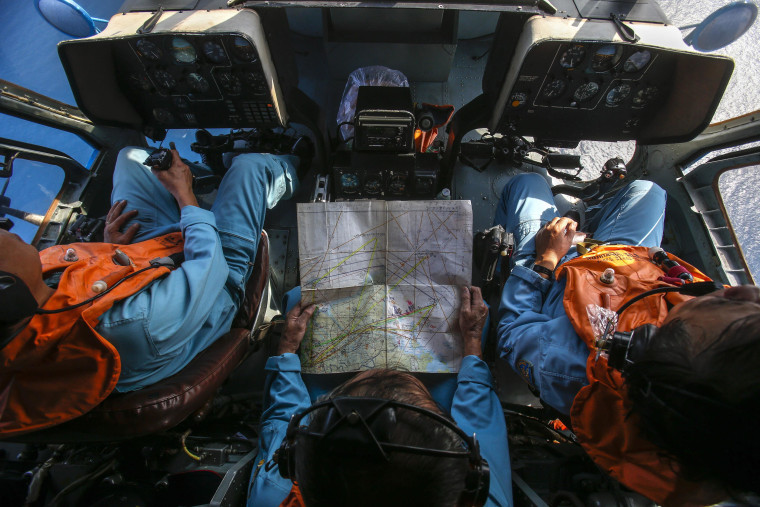 Military personnel work within the cockpit of a helicopter