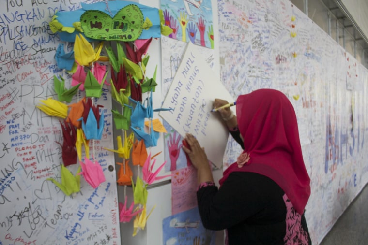 People writing messages for the passengers aboard missing Malaysia Airlines flight MH370 at the international airport in Kuala Lumpur.