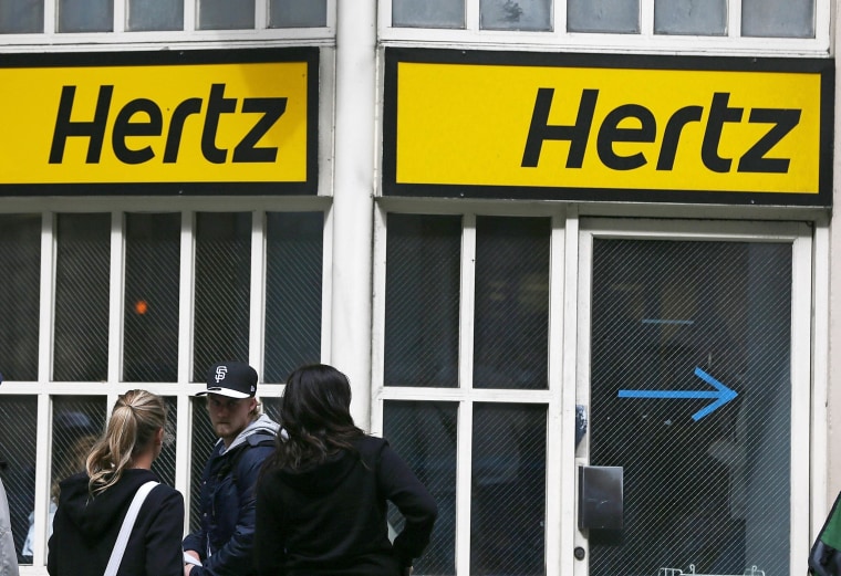 People walk by a Hertz rental car office in San Francisco. 