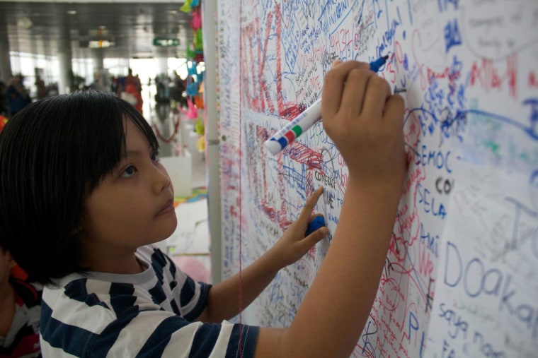 Image: People writing messages for the passengers aboard missing Malaysia Airlines flight MH370 at the international airport in Kuala Lumpur.