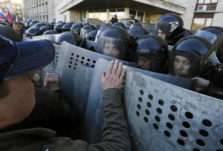 Image: Pro-Russian protesters push Ukrainian riot policemen guarding the regional administration building in central Donetsk