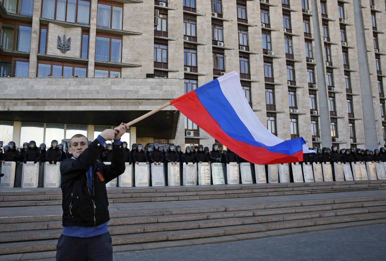 Image: A pro-Russian protester waves a Russian flag in front of riot policemen in Donetsk