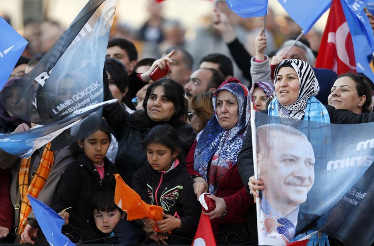 Image: Supporters of Turkey's Prime Minister Tayyip Erdogan wave his portraits and Turkish and his ruling Ak Party (AKP) flags during an election rally in Ankara