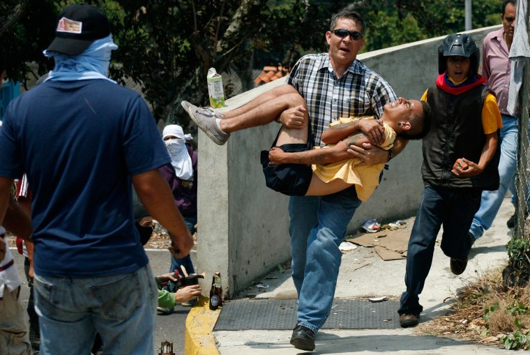 Image: A man carries an injured anti-government protester in San Cristobal