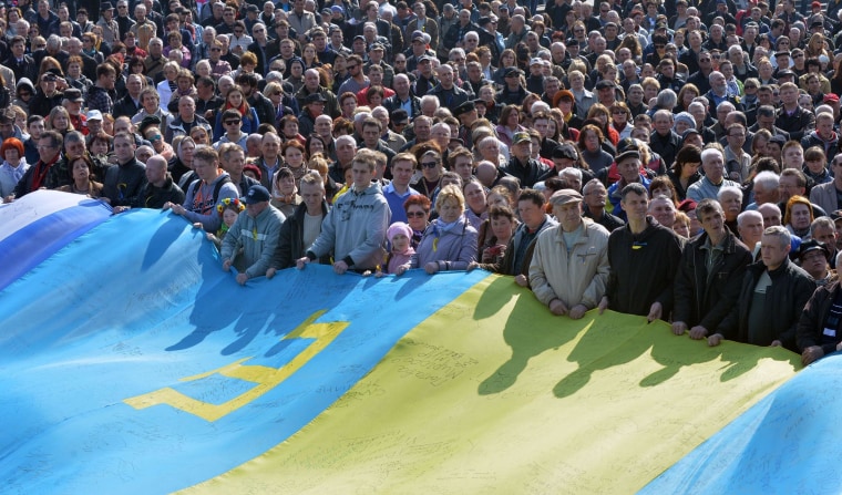 People hold a huge flag, a combination of a Ukrainian, Crimean and Tatar flags, on Independence Square in Kiev on March 23, 2014. 