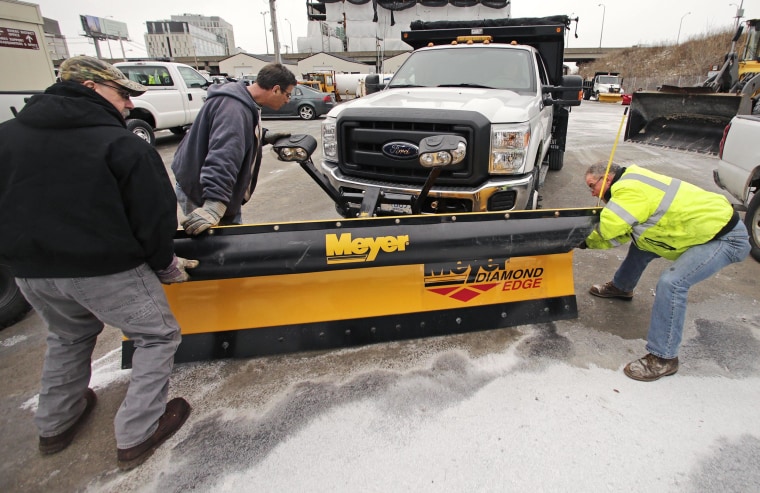 Image: Workers from the Mass. Dept. of Conservation and Recreation put a plow on a truck ahead of an expected winter snow storm in January