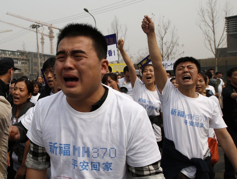 Image: Family members of passengers onboard Malaysia Airlines MH370 cry as they shout slogans during a protest in front of the Malaysian Embassy in Beijing