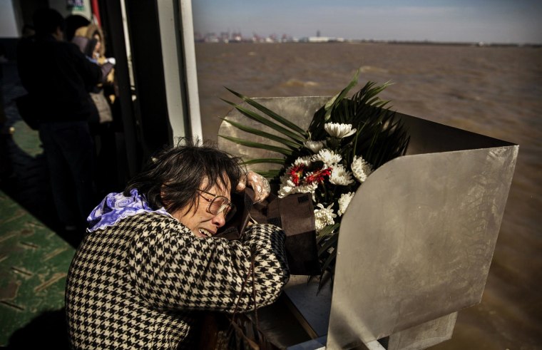 Image: Lin Hui Zhen, 76 years, weeps as she clutches the small bag carrying the ashes of her late husband Fu Yao Ming, 80 years, before placing them in a metal chute during a sea burial