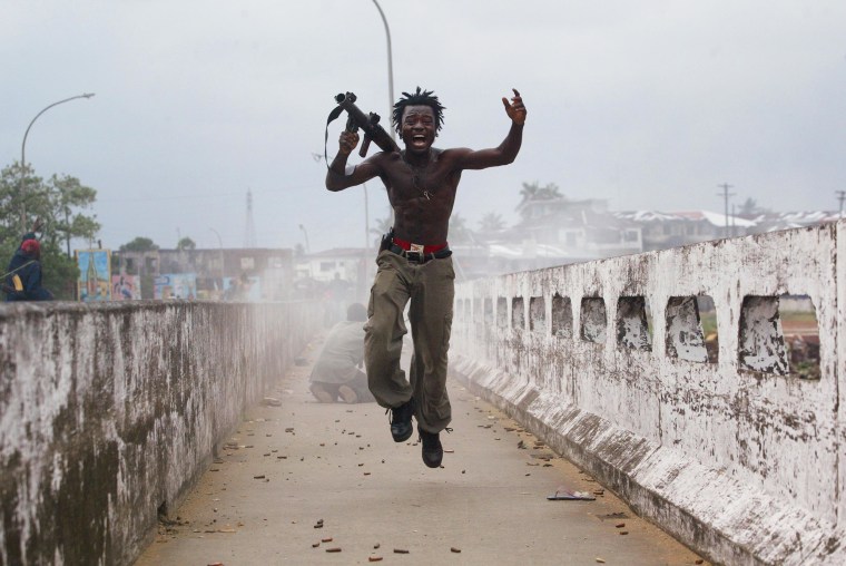 Joseph Duo, a Liberian militia commander loyal to the government, exults after firing a rocket-propelled grenade at rebel forces at a key strategic bridge July 20, 2003 in Monrovia, Liberia. Government forces succeeded in forcing back rebel forces in fierce fighting on the edge of Monrovia's city center.
 
