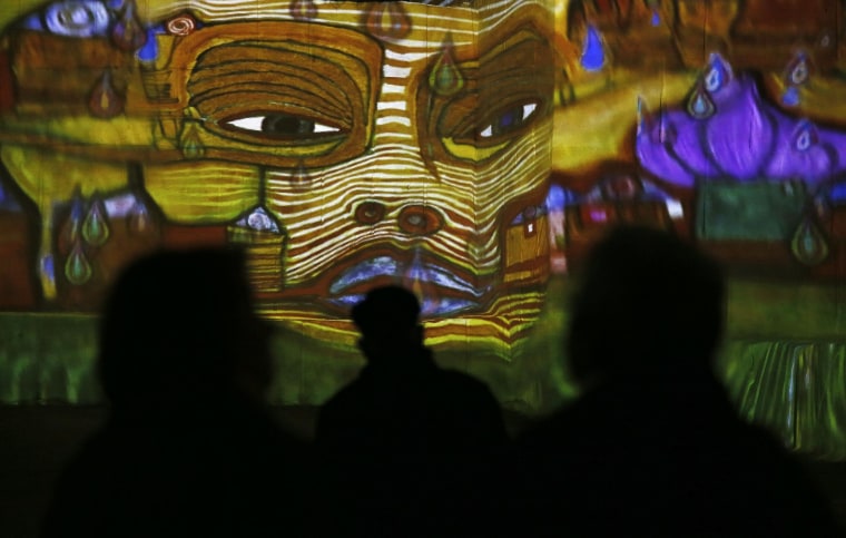 Image: A visitor looks at a sound and light show as part of the exhibition 'Klimt and Vienna, a century of gold and colors', which projected on the walls of the "Carrieres de Lumieres" site (Quarries of lights) in Les Baux-de-Provence