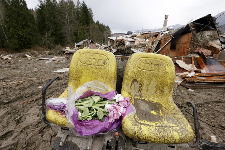 Image: Flowers are left on debris next to a demolished home where a woman's body was found following a deadly mudslide