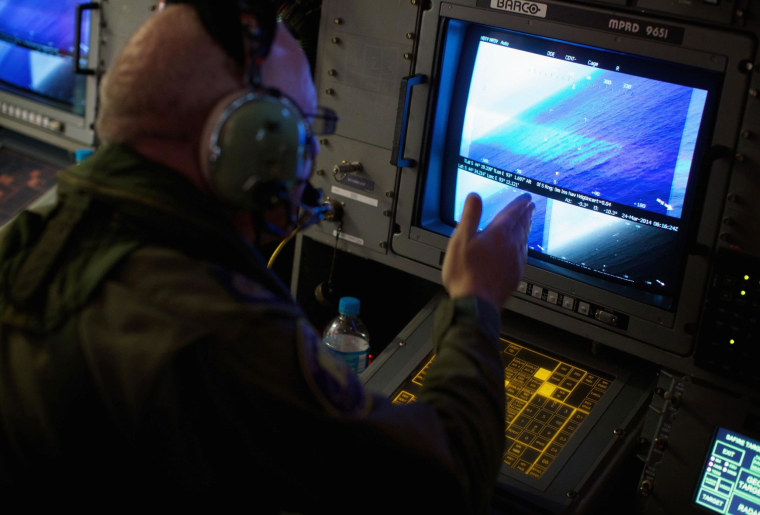 Image: A crewman of a RAAF AP-3C Orion aircraft looks at a screen while searching for missing Boein