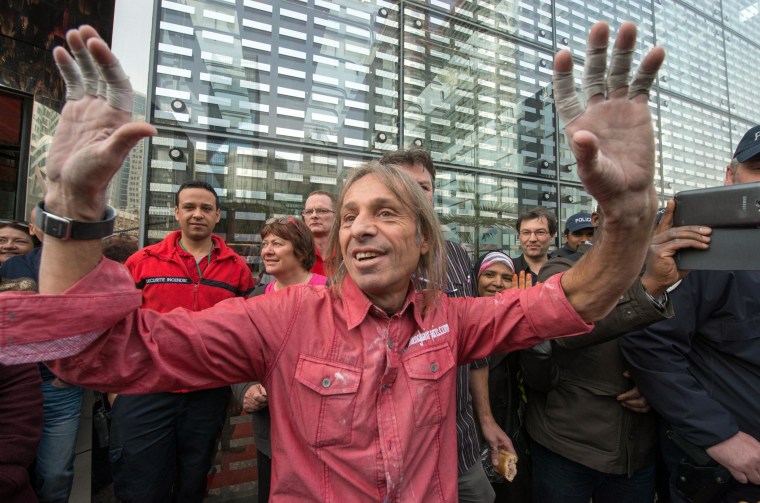 Image: Alain Robert acknowledges the media and onlookers after climbing the Ariane Tower.