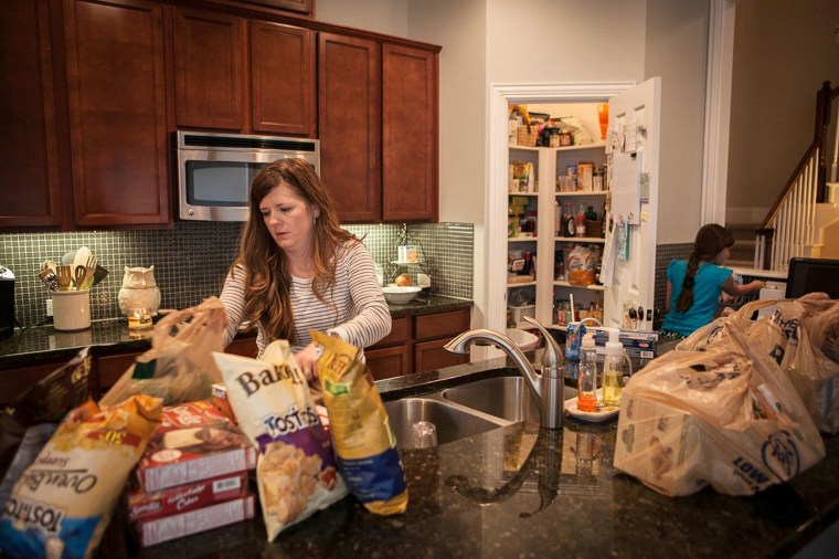 Image: Alice Korey, left, mother of three, unpacks grocery bags from Kroger and uses coupon apps on her iPhone to cut costs of rising food prices at grocery stores