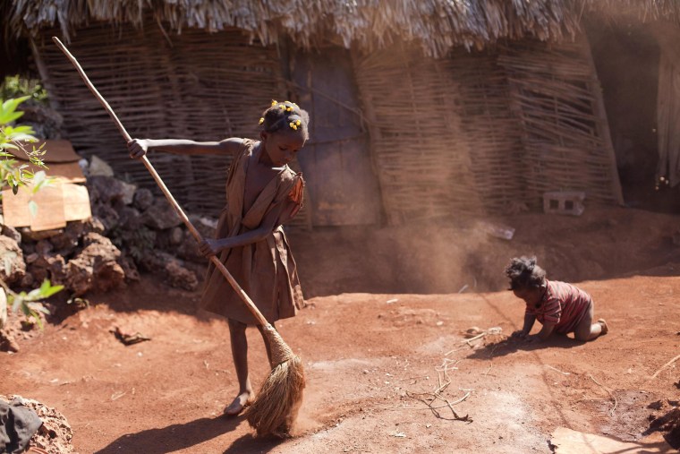 Image:  Larionise Beltinor 10, sweeps the entrance of her home while her 7-month-old brother Jean Widson Beltimor crawls nearby in Bombardopolis, northwestern Haiti.