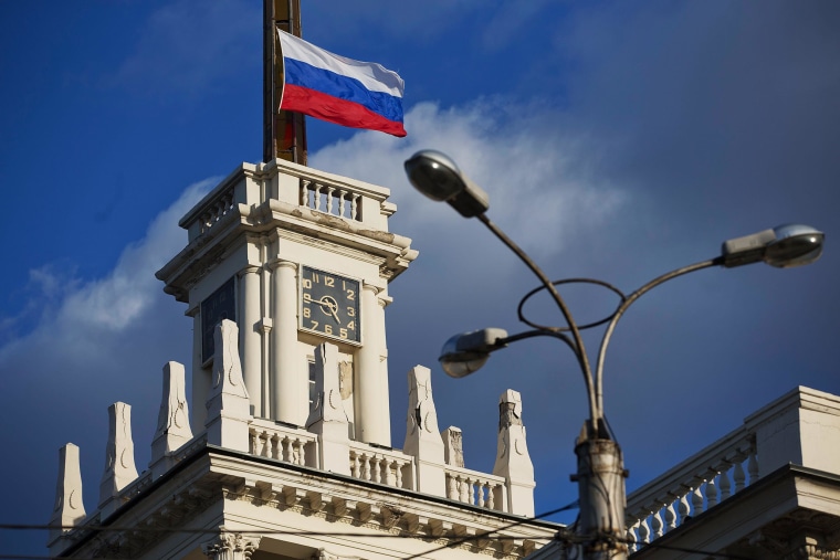 Image: The national flag of Russia flies atop a city clock tower in Sevastopol, Crimea