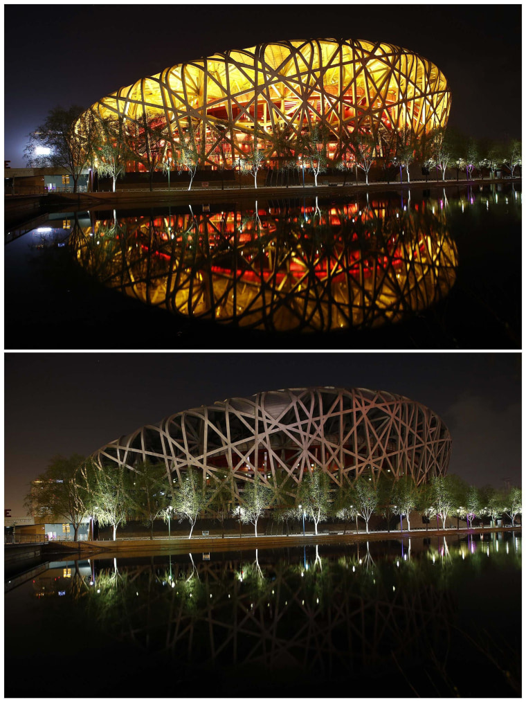 Image: The National Stadium, also known as 'Bird's Nest', reflected in a lake before and during Earth Hour at Olympic Park in Beijing,