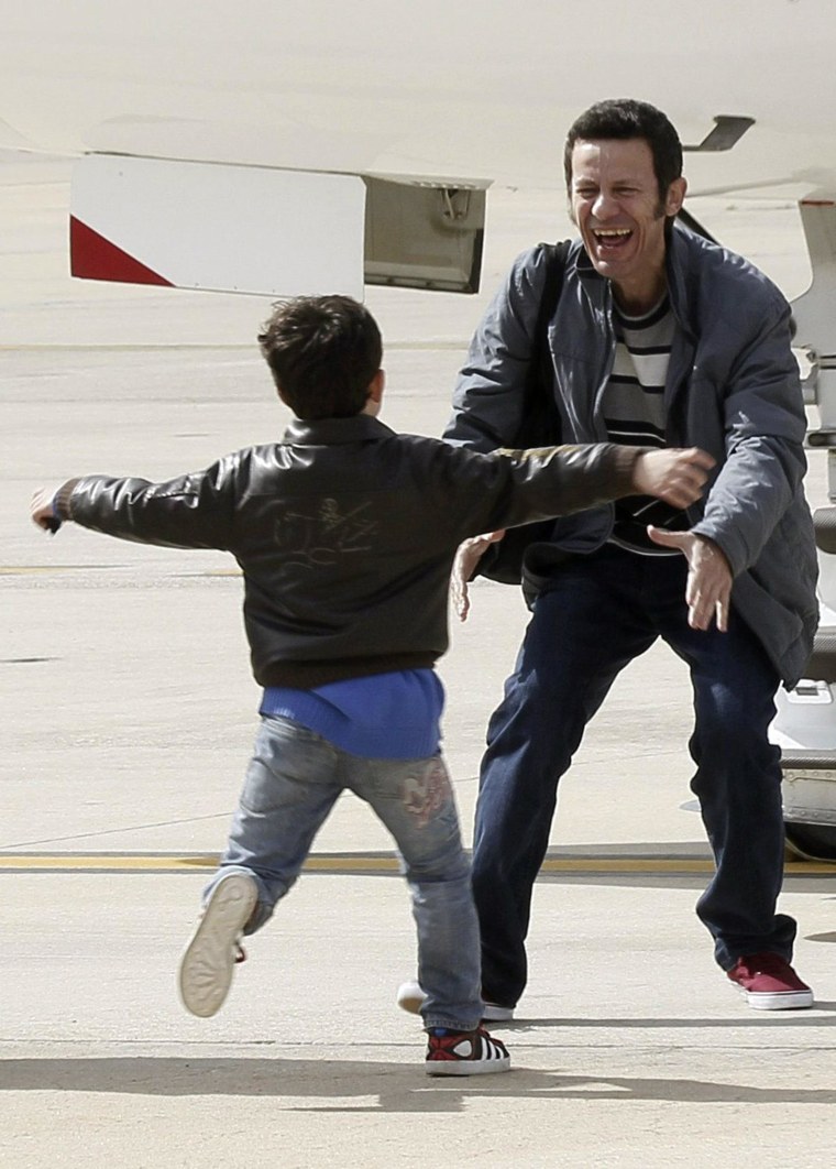 Image: Spanish reporter Javier Espinosa, reacts as his son Yerai runs towards him upon his arrival at the military airport of Torrejon in Madrid