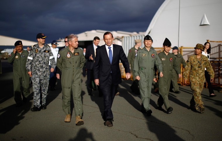 Image: Australia's Prime Minister Tony Abbott walks with Australia's Air Force Group Commander Craig Heap