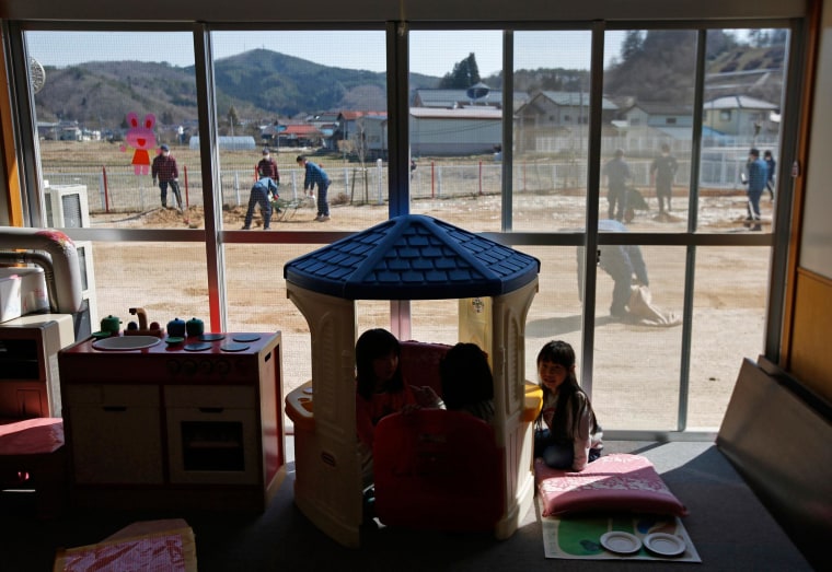 Image: Children play inside a playroom as TEPCO volunteers removed ice and snow and levelled dirt in their playground, at a Miyakoji child care center at Miyakoji area in Tamura