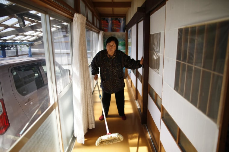 Image: A woman, who evacuated from the Miyakoji area of Tamura three years ago, dusts off her house after she returned to her home in Tamura, Fukushima prefecture