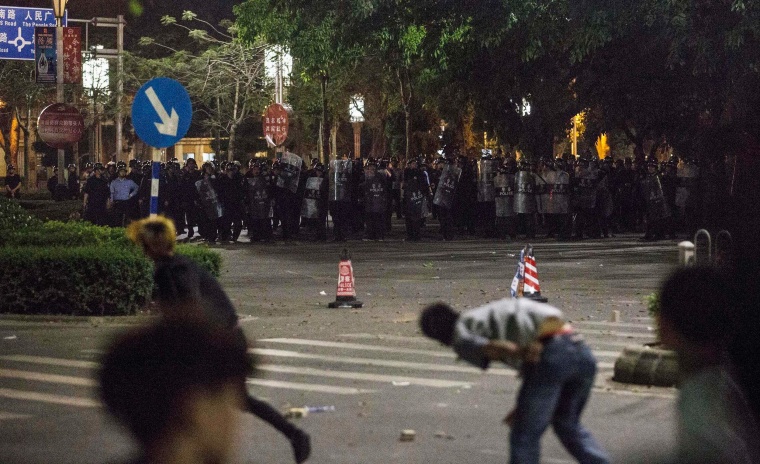 Image: Demonstrators throw bricks at riot police officers, as they protest against a chemical plant project, on a street in Maoming